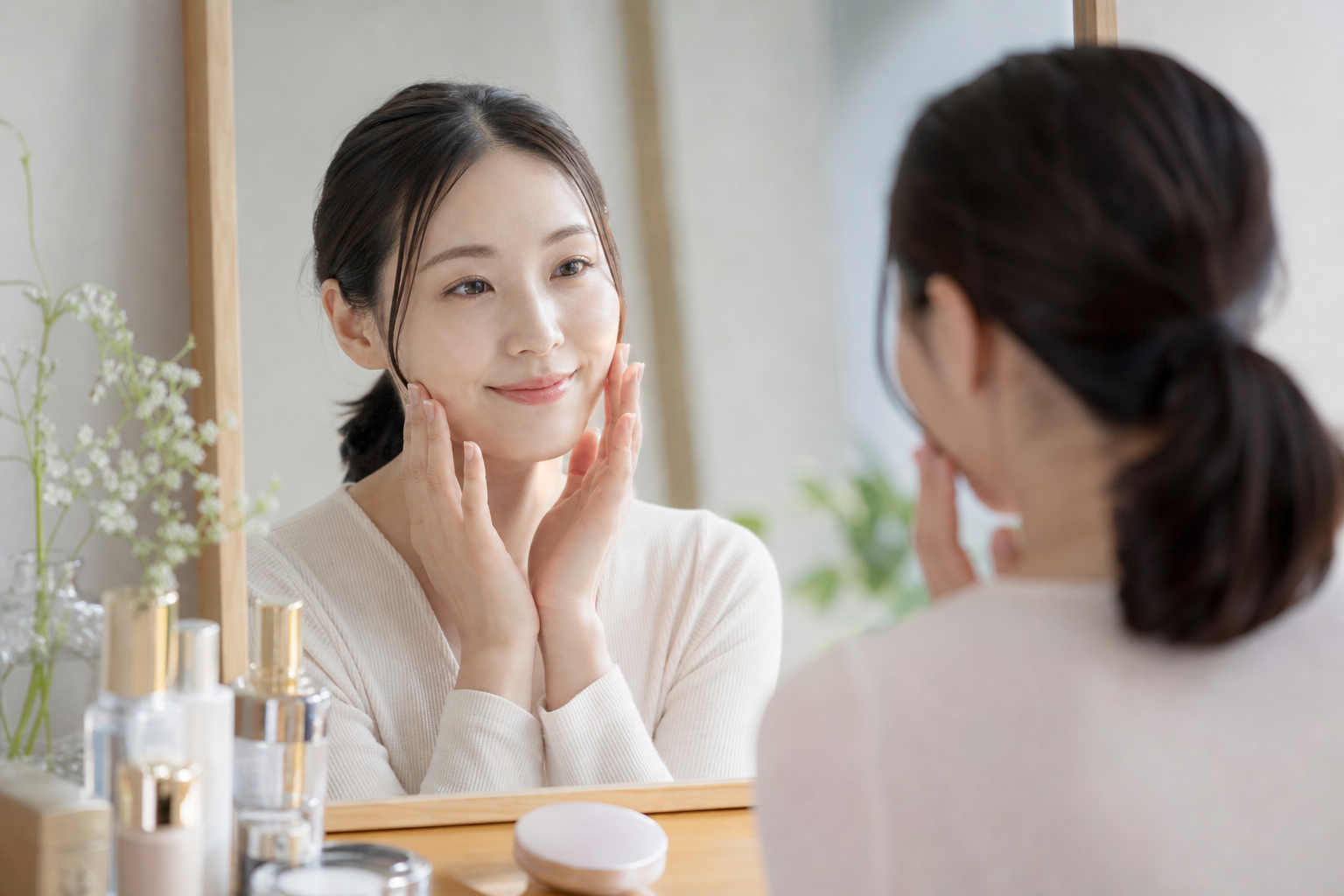 鏡を見ながら肌の状態を確かめる女性